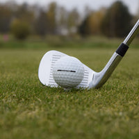 En närbild på en Vice Pro golfboll som är lite upp peggad i gräset framflr en golfklubba.
