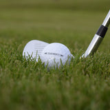 En närbild på Wilson Duo Soft som ligger i gräset framför en golfklubba.
