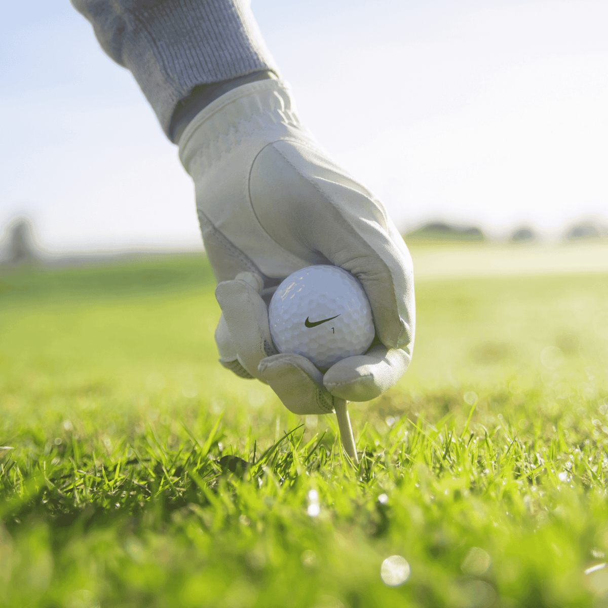 Nike golfboll på peg med en golfare som har en golfhandske på sig. Hos Plikt Golf