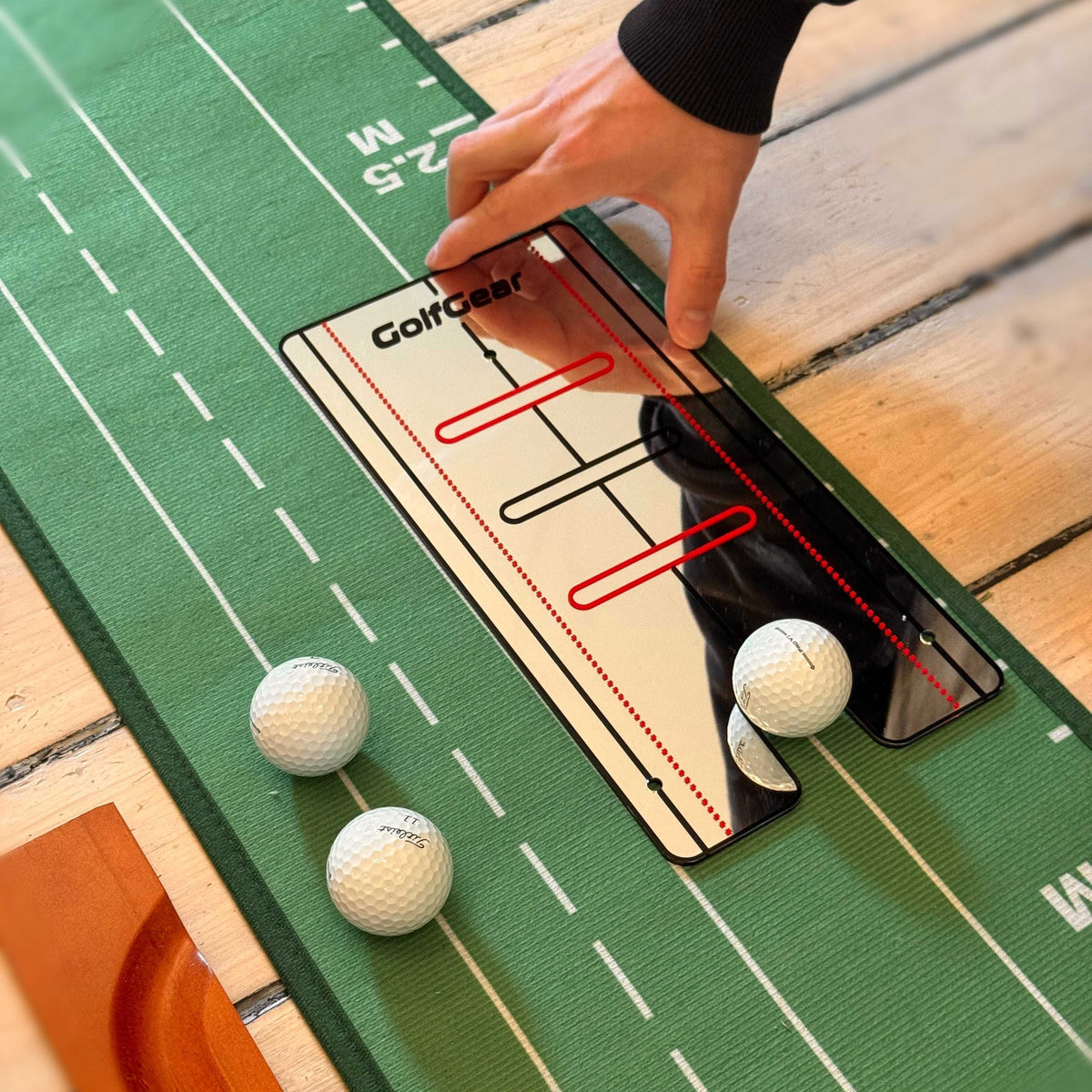 Närbild på Putting Mirror som ligger på en puttmatta med lite golfbollar som visar hur man kan använda den.