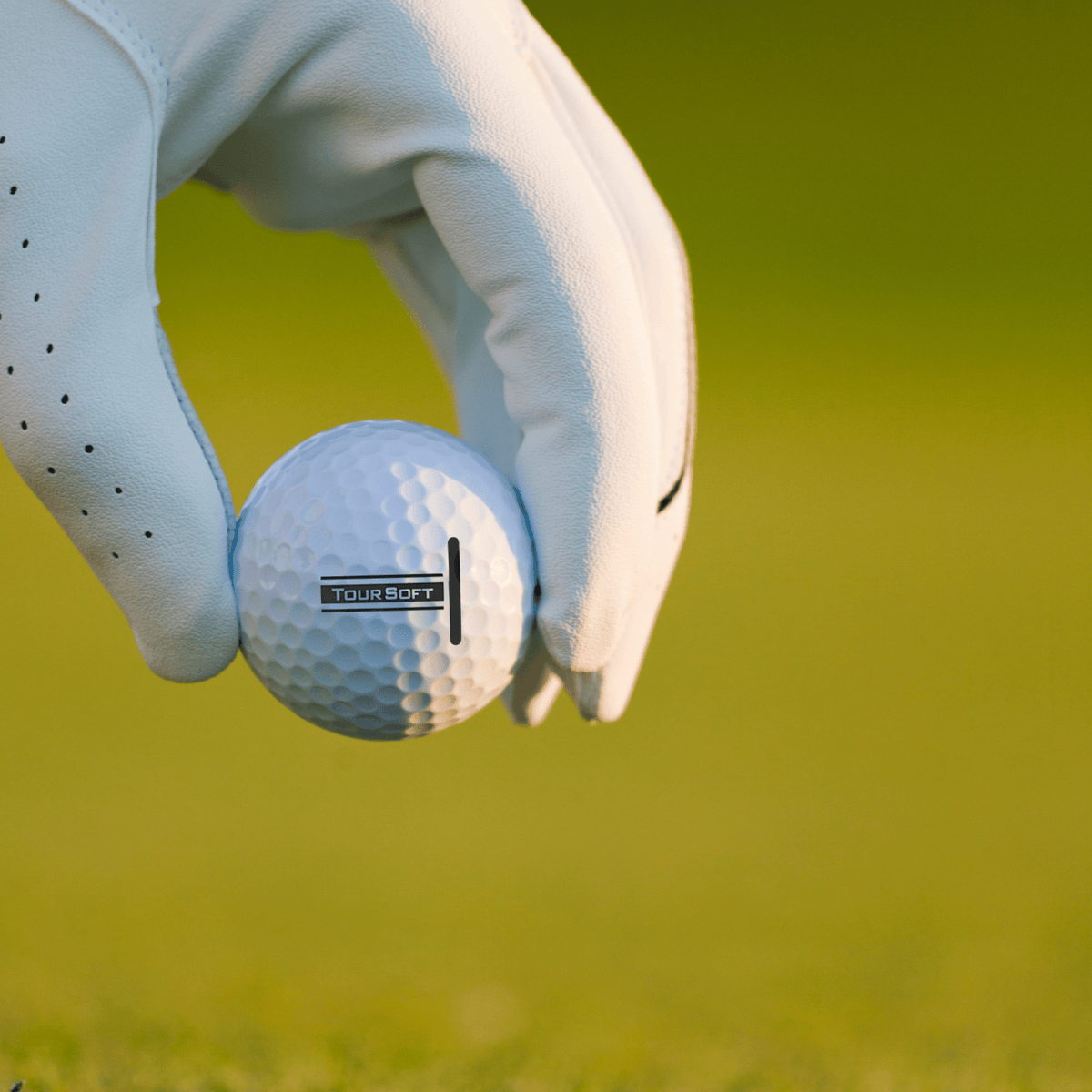 Titleist Tour Soft golfbollar 12-pack som hålls av en golfare med gräs som bakgrund