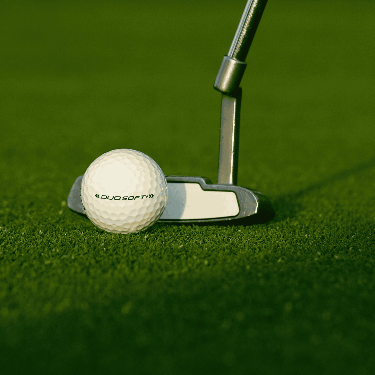 Wilson Duo Soft golfbollar 12-pack på gräs framför en putter